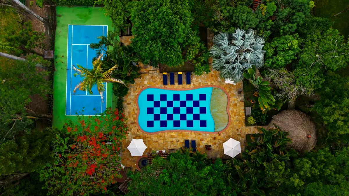 Vista aérea de la piscina de ajedrez y la cancha de tenis entre los jardines de la hacienda